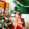 A woman and a girl are hanging the beaded Christmas tree garland to Christmas tree