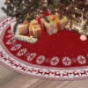 There are many gifts on this red embroidered Christmas tree skirt