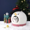 A cat in the Snowman Christmas house ornament is watching you
