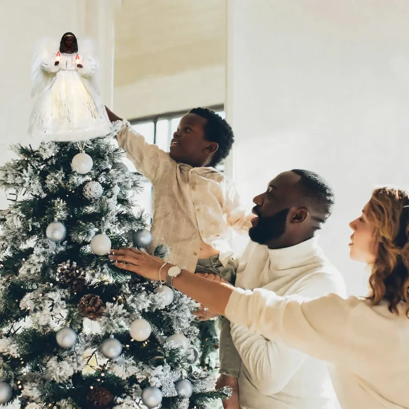 Heartwarming Christmas moment: father helps boy put a gold black angel tree topper while mother looks on smiling