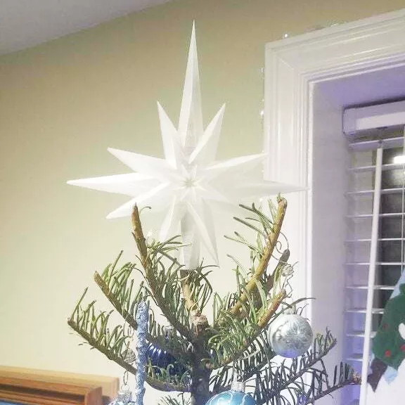 There is a Star of Bethlehem tree topper on top of a Christmas tree