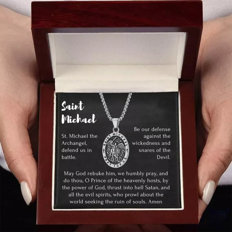 A woman is holding a silver Saint Michael necklace in a luxury box