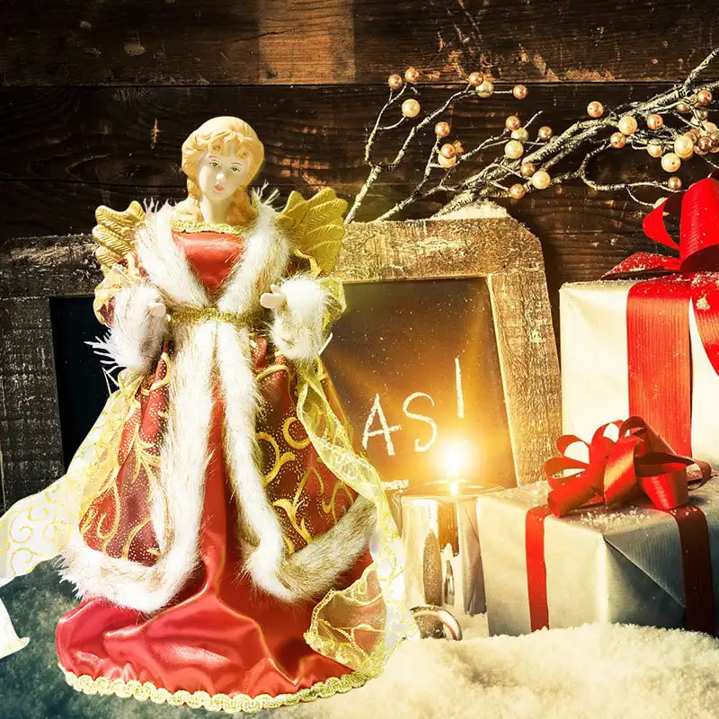 An angel tree topper with golden wings stands on a mat.