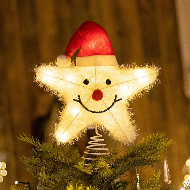 A smiley face star tree topper with a Santa hat stands on the tree.