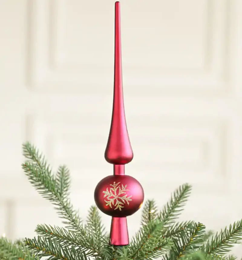 A red Christmas tree finial topper stands on the tree.