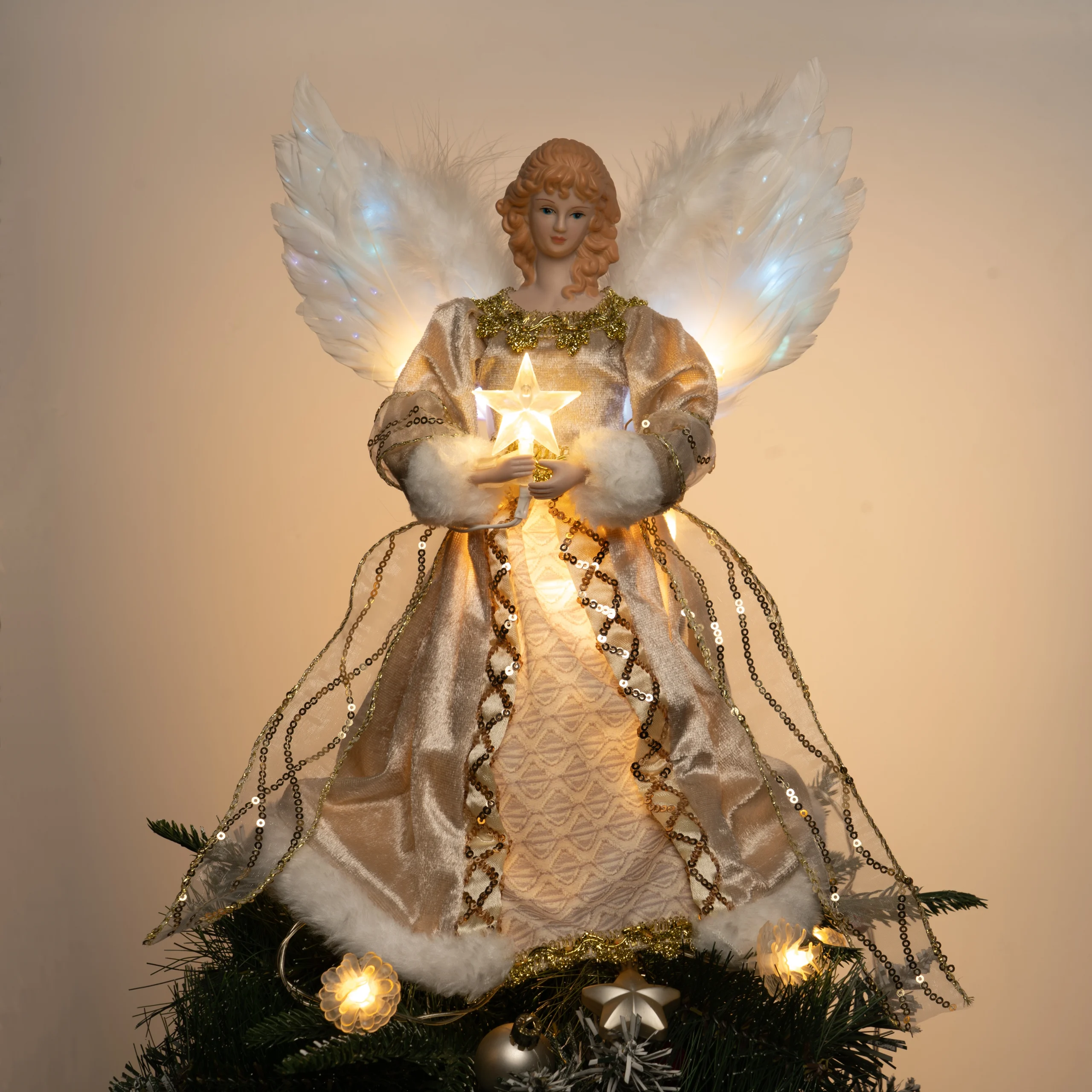 Gold fiber optic angel Christmas tree topper, white feather fiber-optic wings, warm glowing star, placed on Christmas tree